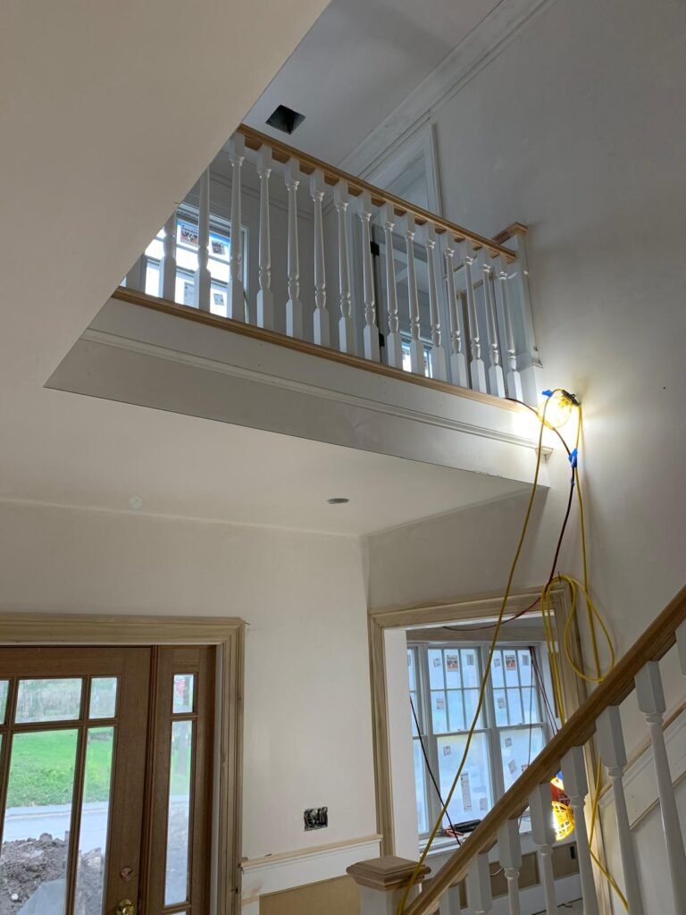 Upper landing railing with white balusters by WHB Construction Corp.