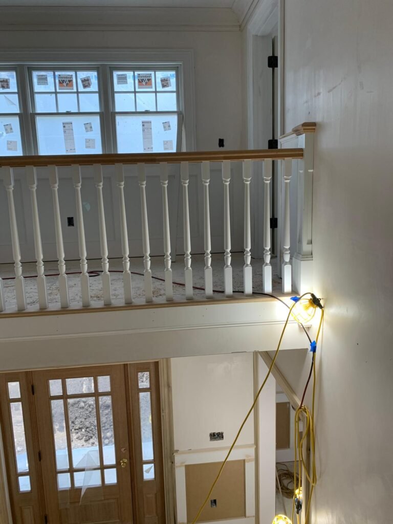 Balcony railing with white balusters above the front door by WHB Construction Corp.