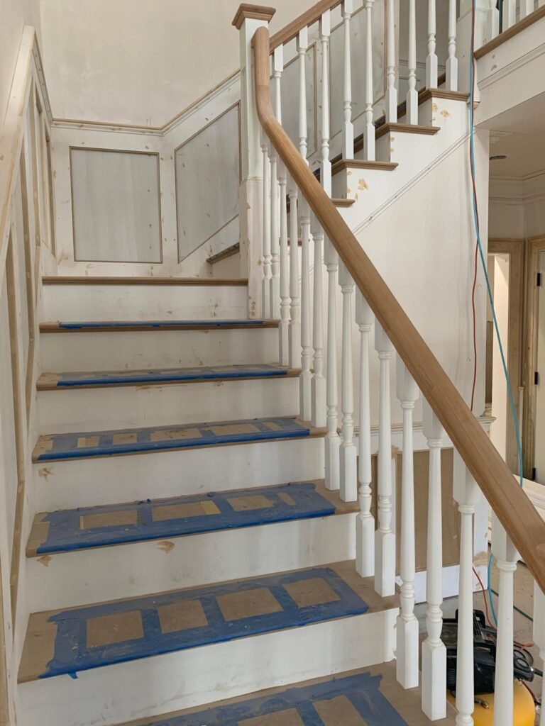 Staircase with oak handrail and wainscoting by WHB Construction Corp.