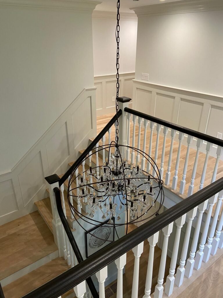 Finished staircase railing with black handrail and white balusters by WHB Construction Corp.